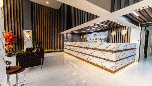 A reception desk with a marble top and wooden paneling, a leather sofa, and a potted plant. - Blue Vista Houses & Spa (Istanbul)