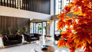 A modern lobby with a central round table, seating arrangements, and a decorative autumn leaf installation. - Blue Vista Houses & Spa (Istanbul)