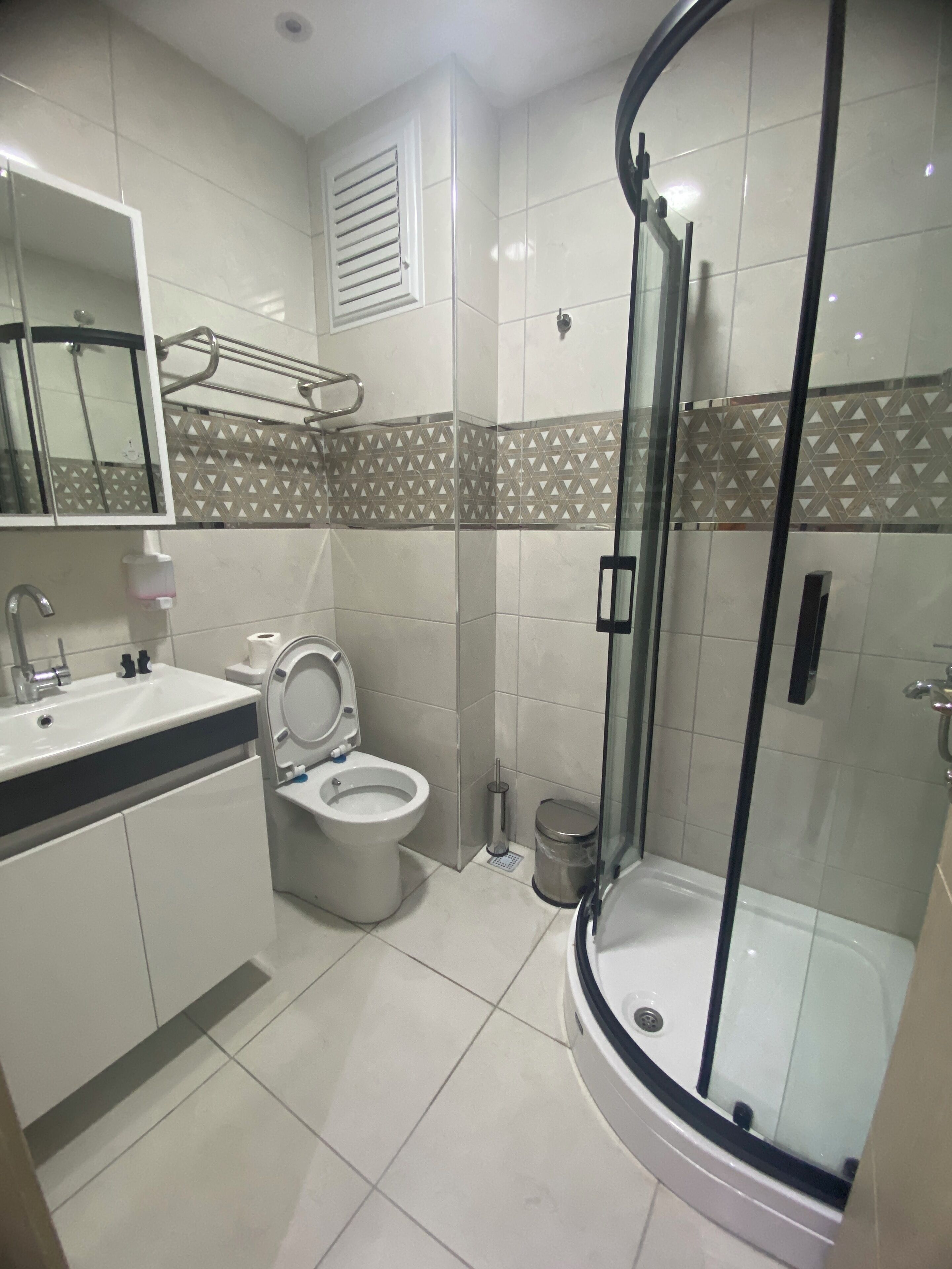 A modern bathroom with a toilet, sink, and glass-enclosed shower.