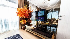 A modern living room with a large flat-screen TV, a decorative plant, and a vintage clock on a wooden cabinet. - Blue Vista Houses & Spa (Istanbul)