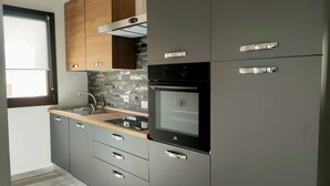 A modern kitchen with grey cabinets, a black oven, and a wooden countertop. - Suite Apartments i4MORI Porto Pino (Sant'Anna Arresi)