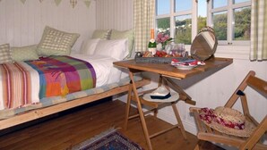 A cozy bedroom with a bed, a wooden desk, a chair, and a window with curtains.