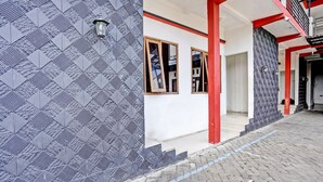 Un edifici amb parets exteriors de disseny, elements estructurals vermells i una zona d'entrada pavimentada.