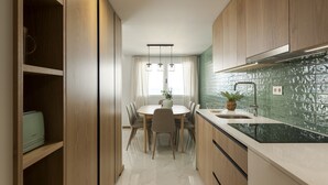 Una cocina moderna con armarios de madera, encimera de mármol y comedor con mesa y sillas.