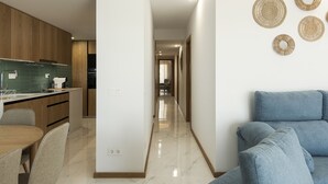 Una cocina moderna con armarios de madera, un comedor con mesa y sillas, y un pasillo que conduce a una sala de estar con un sofá azul.