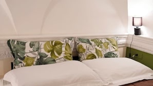 Un lit avec du linge de lit blanc et une tête de lit à motifs floraux.