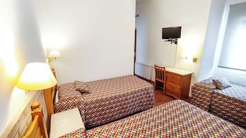 A hotel room with two beds, a desk, a chair, a TV, and a window.