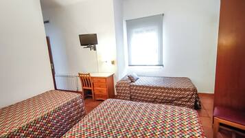 Een kamer met twee bedden, een bureau, een stoel, een televisie en een raam.
