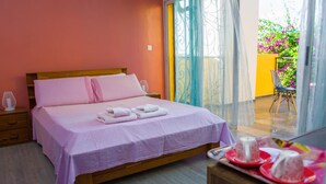 A bedroom with a bed, bedside tables, a chair, and a balcony with a view of flowers. - Room-the White-orange Bedroom With a ple (Antananarivo)