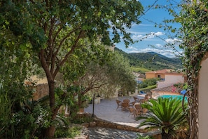 A courtyard with stone flooring, outdoor seating, and a pool.