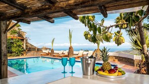 A poolside area with a view of the ocean, lounge chairs, and a fruit and champagne setup. - Leyla Luxury Villa with Spinalonga View (Vrouchas)