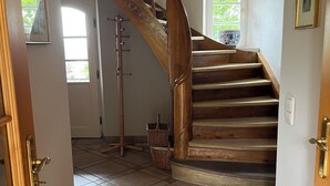 A wooden staircase with a handrail, leading to a landing with a window.