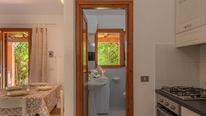 A compact kitchen with a gas stove, a sink, and a window overlooking greenery.