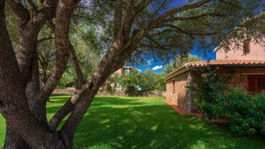 A stone building with a tiled roof, surrounded by a well-maintained lawn and trees.