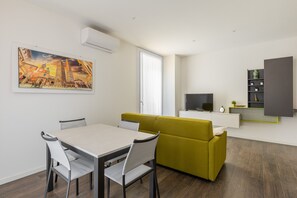 Un salon moderne comprenant un coin repas, un canapé, un téléviseur et un tableau accroché au mur.
