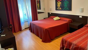 Habitación de hotel con una cama grande, un escritorio y una silla. Hay una ventana con cortinas, un cuadro en la pared y una lámpara sobre la cama.
