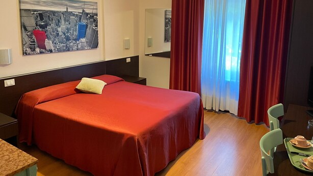 Una habitación de hotel con una cama, una zona de comedor y un cuadro de paisaje urbano en la pared.