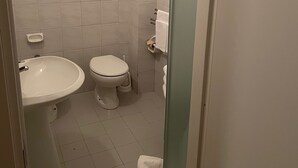 Un baño con lavamanos, inodoro y cabina de ducha de vidrio.