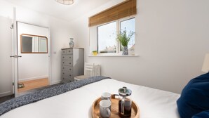 A bedroom with a bed, a dresser, a window with a view, and a tray with cups and a coffee pot. - Tas Gwynn -  a house that sleeps 4 guests  in 2 bedrooms (St Buryan)