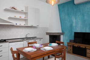 A modern kitchen with white cabinets, a granite countertop, and a dining table set for four. - Casa Bata by Wonderful Italy (Budoni)