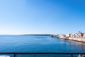 Une vue sur la côte, avec un ciel dégagé, une mer calme et des bâtiments qui bordent le rivage.