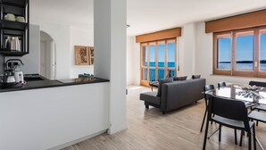 En modern lägenhet med kök, matplats och en balkong med utsikt över havet.