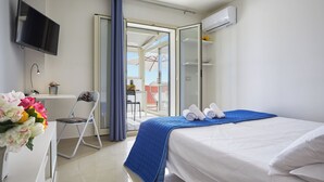 A hotel room with a bed, a TV, a chair, a desk, and a view of the outside. - Nice Studio on the Terrace (Pozzallo)