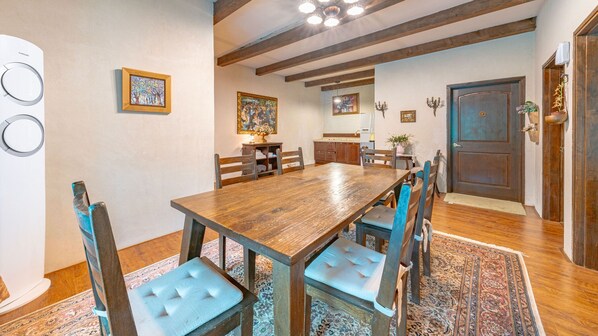 A dining area with a wooden table and chairs, a kitchen in the background, and a door with a decorative handle. - Gapyeong Labelle Pension (Gapyeong)