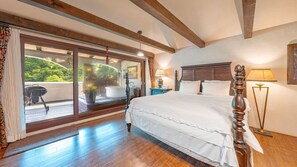 A bedroom with a large sliding glass door leading to a balcony, a wooden ceiling, a bed with white linens, and a nightstand with a lamp. - Gapyeong Labelle Pension (Gapyeong)