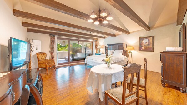 A spacious bedroom with a large bed, a wooden chair, a table with a vase, and a view of a balcony. - Gapyeong Labelle Pension (Gapyeong)