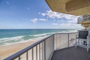 A balcony with a view of the beach and ocean.