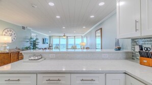 A spacious kitchen with a large island, white cabinetry, and a view to the outside.