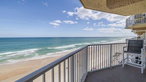 A balcony with a view of the beach and ocean.