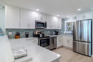A modern kitchen with white cabinets, stainless steel appliances, and a tiled backsplash.
