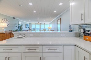 A spacious kitchen with a large island, white cabinetry, and a view to the outside.
