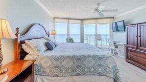 A bedroom with a large bed, a desk, and a TV.