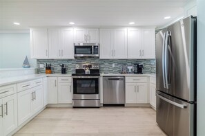 A modern kitchen with white cabinets, stainless steel appliances, and a tiled backsplash.