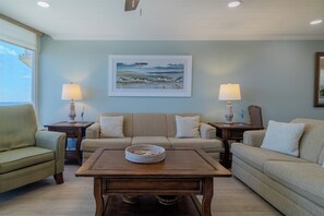 A living room with two sofas, a coffee table, and lamps. There is a framed picture on the wall.