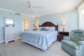 A bedroom with a bed, a dresser, a chair, and a ceiling fan.
