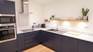 Ett modernt kök med mörka skåp, en inbyggd mikrovågsugn, en brödrost och en kaffebryggare.