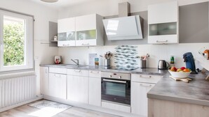 A modern kitchen with white cabinets, a built-in oven, and a window providing natural light.