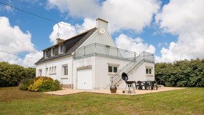 A white house with a balcony, a garage, and a barbecue setup.