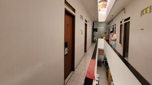 Ein Hotelkorridor mit Holztüren, einer Treppe und einem roten Handtuch auf dem Boden.