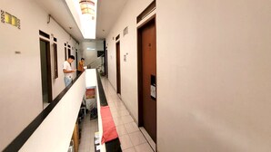 Ein Hotelflur mit Treppe, Türen und einer Person, die am Geländer steht.