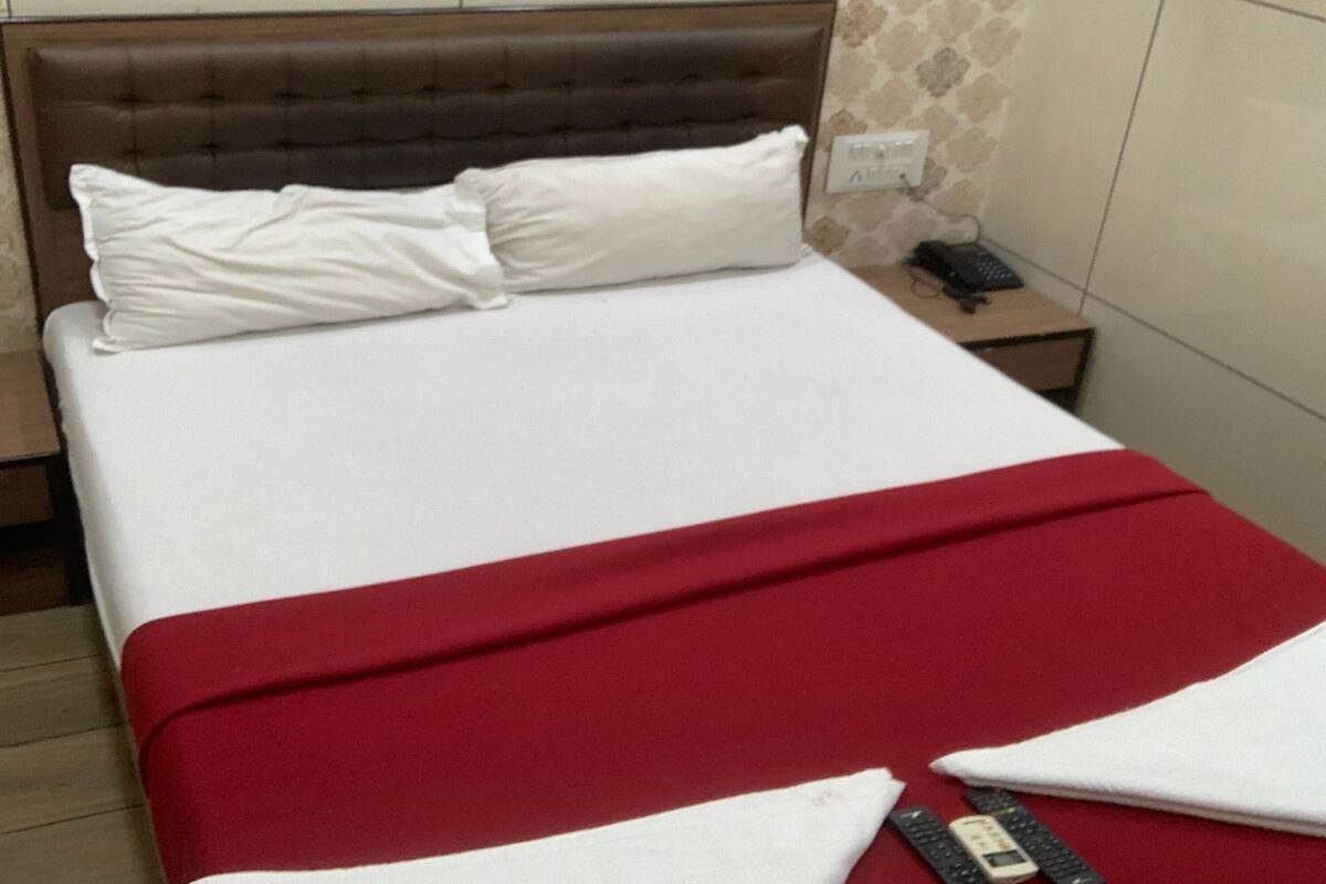 Een hotelkamer met een bed, een nachtkastje en een muur met een decoratief patroon.