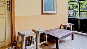 A room with a table and two stools, a door, and a window with a view of greenery. - Hotel O Lili Kost SyariahNearKetapang Royal City (Banyuwangi)