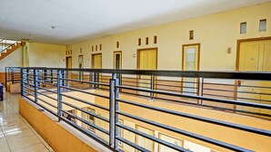 A corridor with a metal railing, yellow walls, and doors with windows. - Hotel O Lili Kost SyariahNearKetapang Royal City (Banyuwangi)