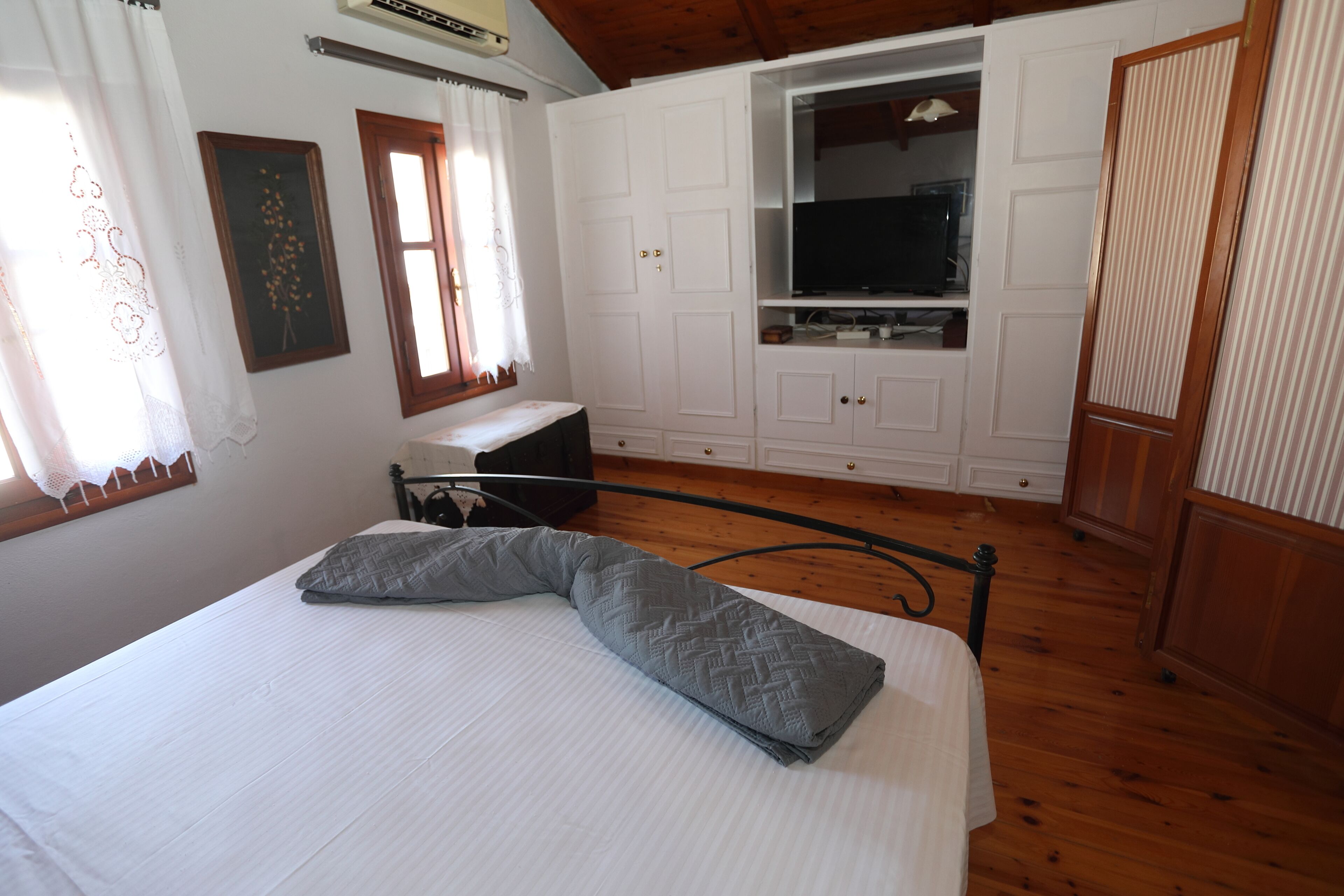 Une chambre à coucher avec un lit, une télévision et une armoire.