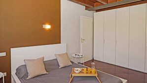 Quarto com cama, mesa de cabeceira e bandeja com itens de café da manhã.