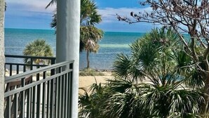 A balcony with a view of the ocean and palm trees. - Stunning Ocean View 2BR/2BA Condo in Exclusive 1800 Atlantic Community (Key West)